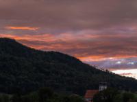 Dunkle Aschauer Berg Flanke mit orange leuchtenden Abendwolken darüber